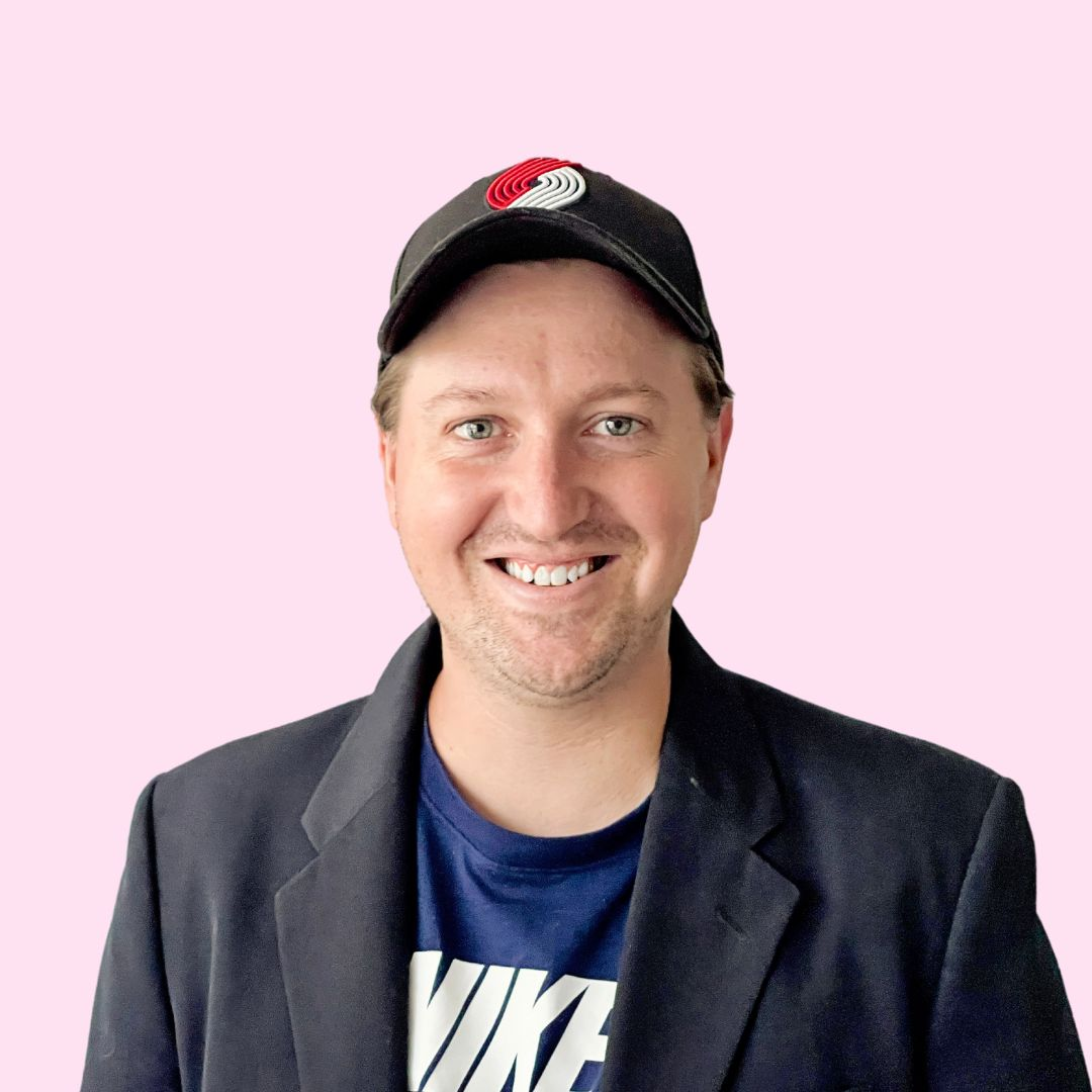DIY headshot of man in a cap against a light pink background.