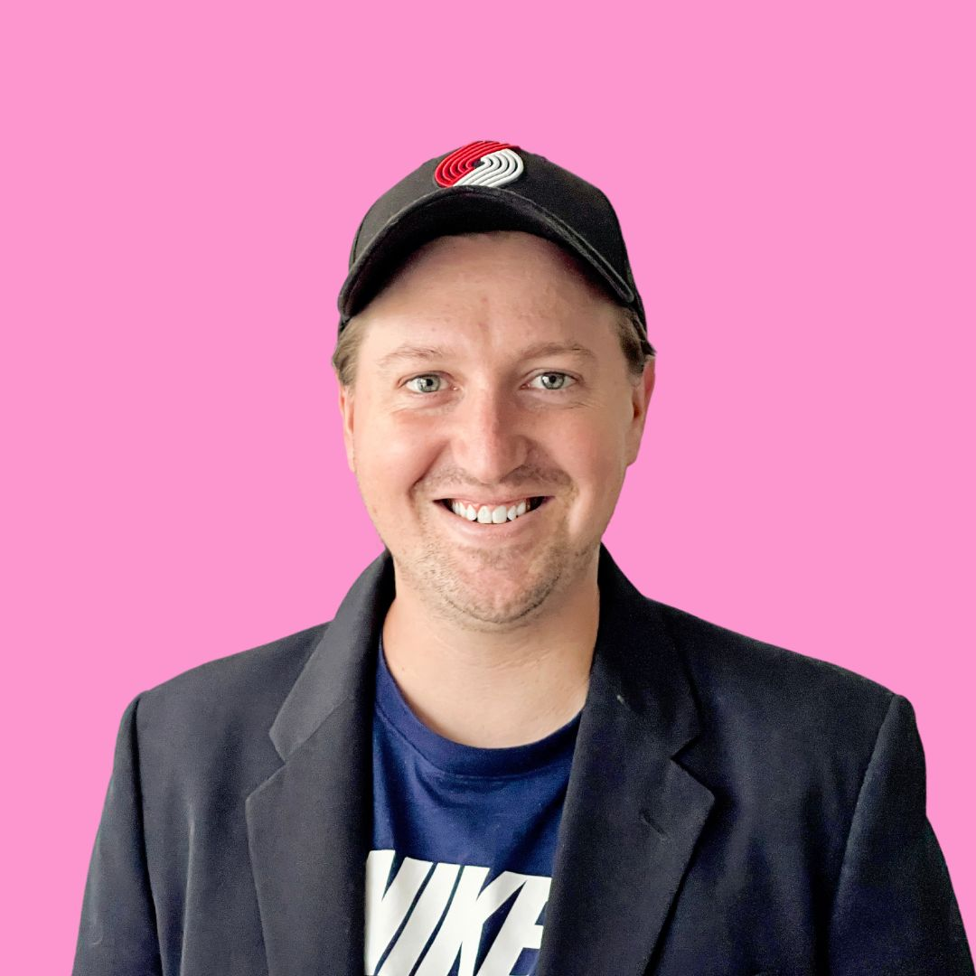 DIY headshot of man in a cap against a hot pink background.