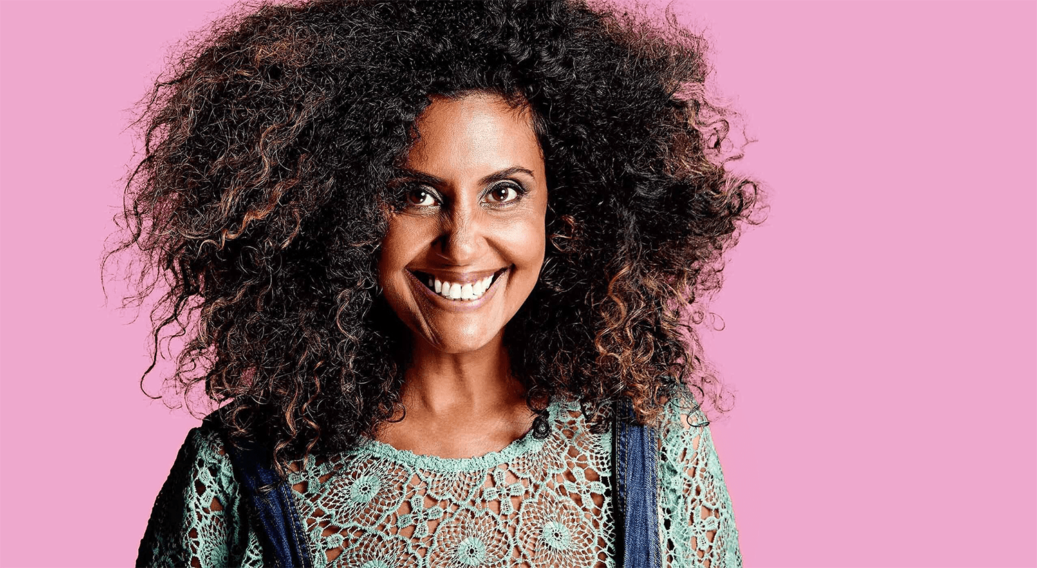 Example image of Natalie Gillespie with an off centre crop.  Natalie has an affro and is wearing overalls against a hot pink background.