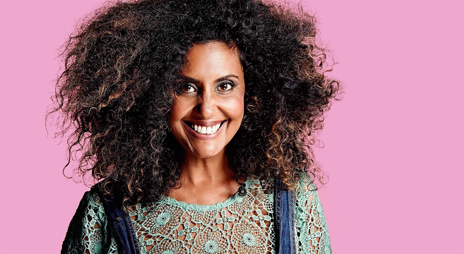Example image of Natalie Gillespie with an off centre crop.  Natalie has an affro and is wearing overalls against a hot pink background.
