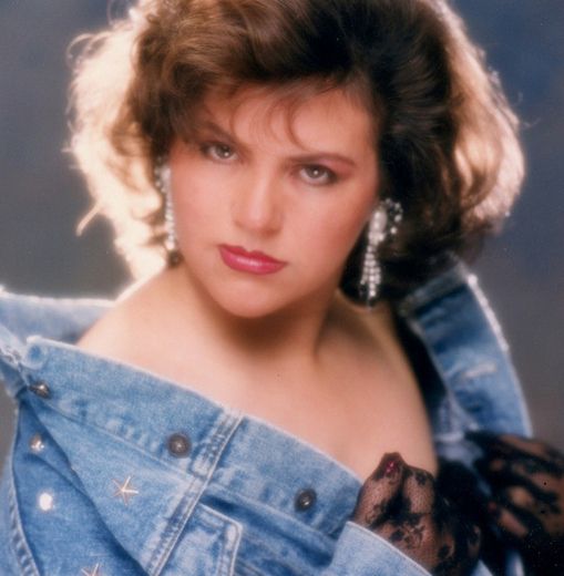 Example of an 80s glamour type headshot.  The woman is wearing denim with big hair and over the top hair lighting.