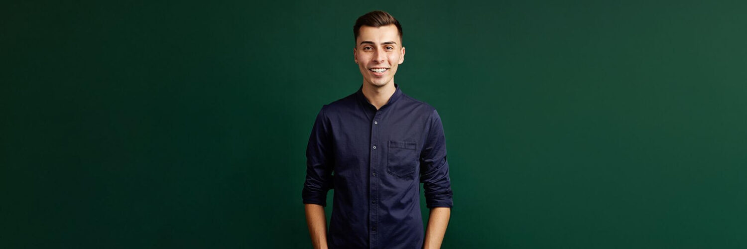 Example of forrest green background used in studio photoshoots. Man is wearing a navy shirt and smiling at camera. All headshots are by Photoform*.